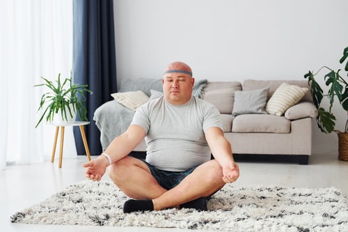 doing-yoga-exercises-funny-overweight-man-casual-clothes-is-indoors-home