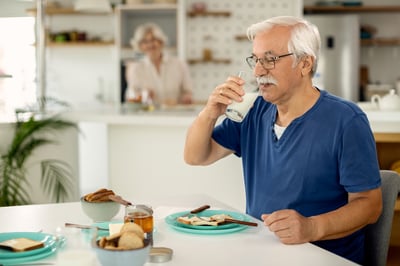 hombre-maduro-bebiendo-leche-mientras-desayuna-casa