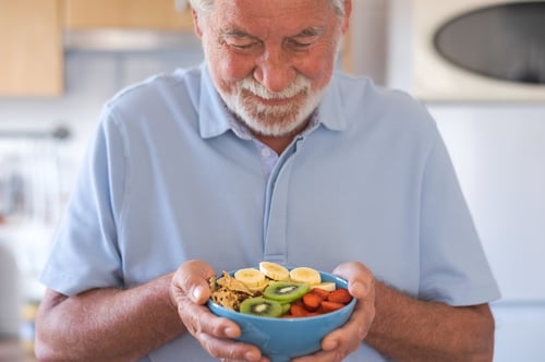 hombre-mayor-sonriente-listo-comer-ensalada-frutas-frescas-secas-desayuno-o-almuerzo-alimentacion-saludable