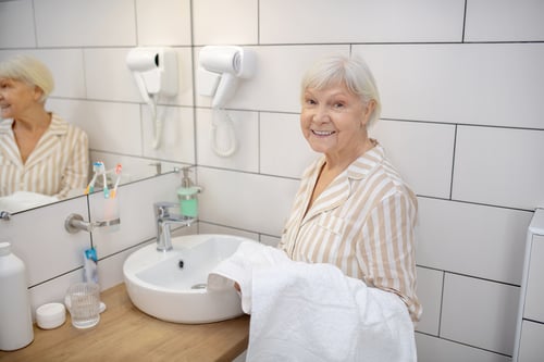 morning-routine-gray-haired-woman-bathroom-with-towel-hand